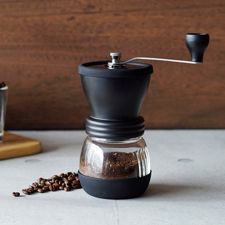 Molino de café manual Hario Skerton Bloom con muelas de cerámica y manivela de acero inoxidable, diseño compacto y capacidad para 100g.