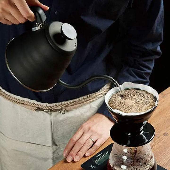 Persona vertiendo agua caliente para café con báscula Hario con temporizador debajo del filtro.